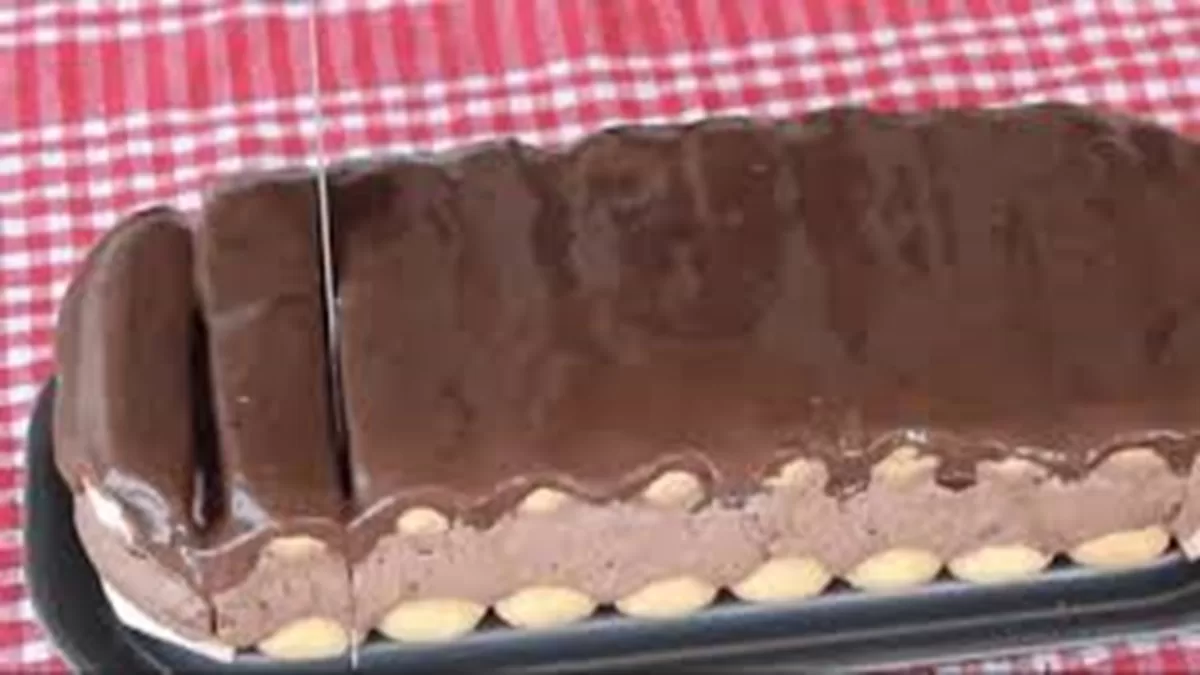 Čokoládový nepečený dezert s piškótami a smotanou na podnose, pripravený na krájanie.