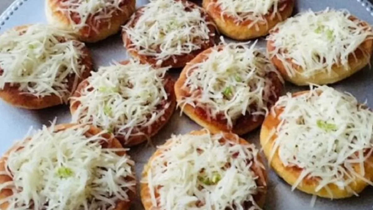 Domáce langoše potreté cesnakom, paradajkovou omáčkou a posypané strúhaným syrom na tanieri.